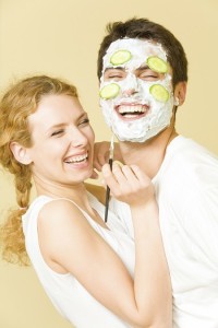 Young happy joyful couple making facial masque at home