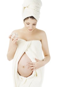 Pregnant woman in spa towels, cream for pregnancy belly, health
